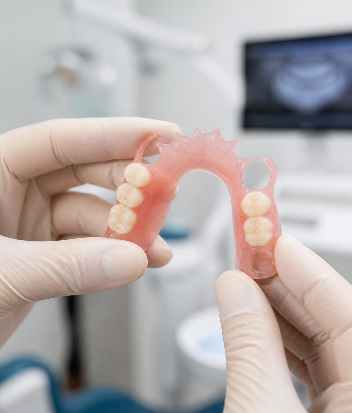 Prótesis dental flexible Valplast sostenida por manos enguantadas